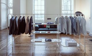 The Jijibaba collection of men's suits and shirts on a long clothing rail in a room with wooden floors and large windows.