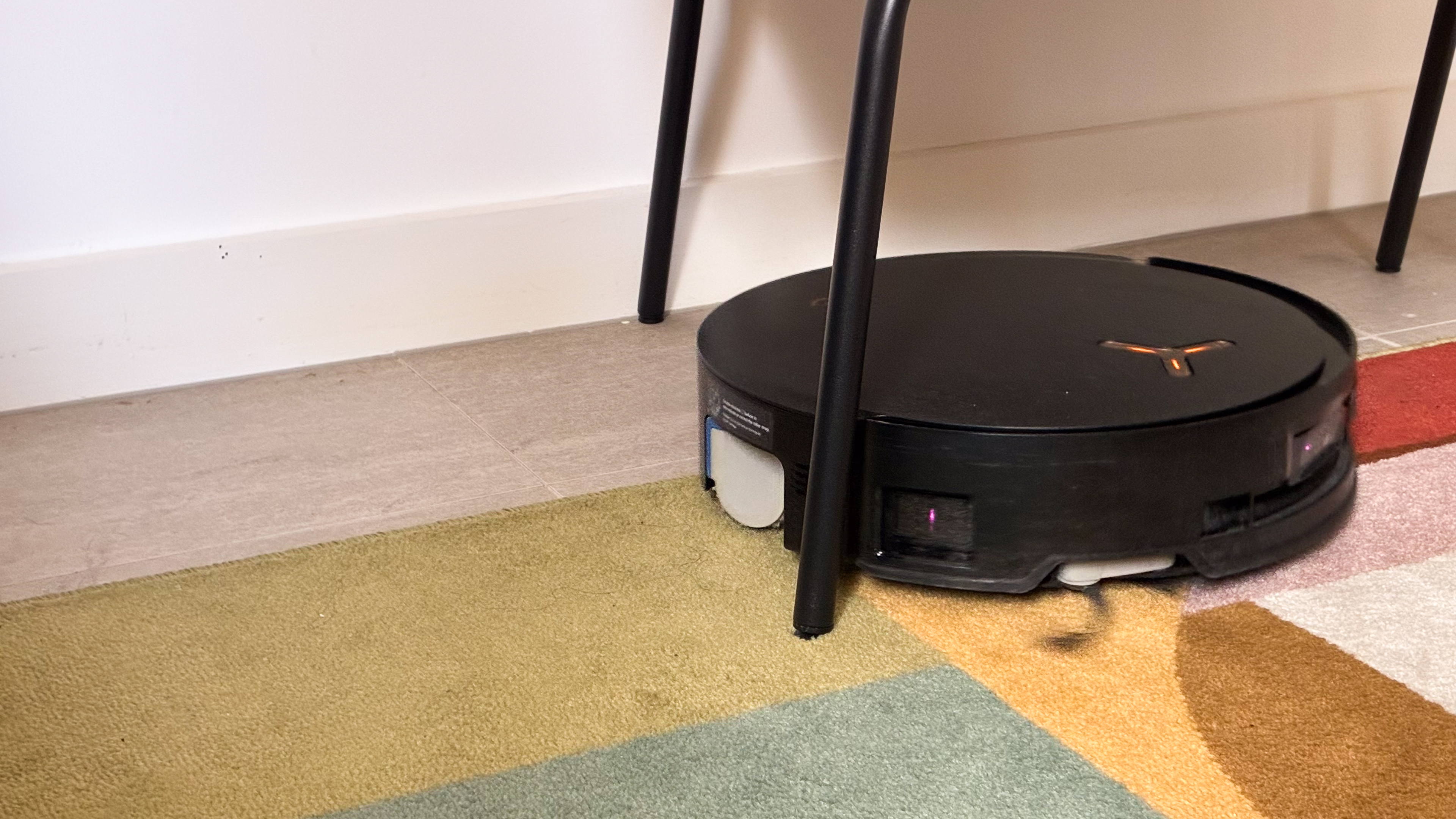 Ecovacs Deebot X8 Pro Omni robot vacuum mopping under a chair on a rug