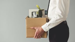 Cropped image of businessman in formal wear holding a box with his stuff