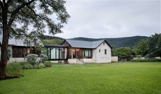 single storey house with glass link and green landscape and hills around