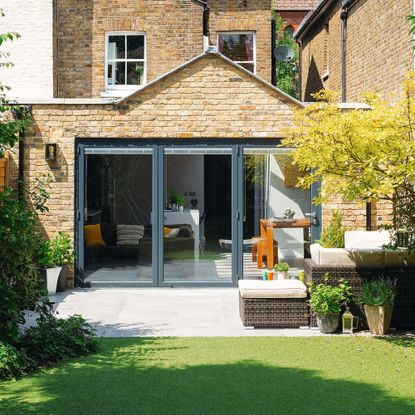 Rear exterior view of a house with a kitchen extension and sliding doors onto the garden and patio