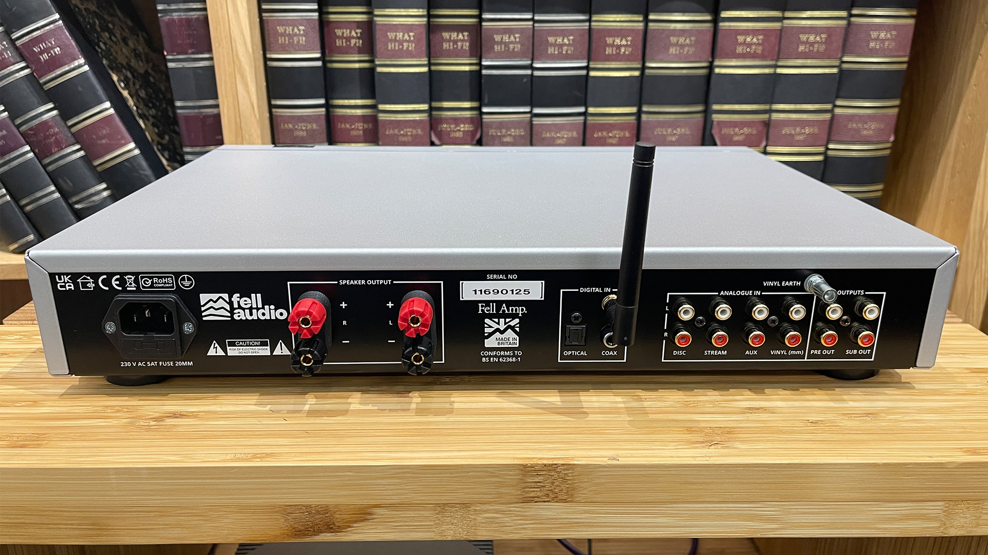 Fell Audio Fell Amp integrated amplifier on wooden hi-fi rack in front of bookcase, rear of unit showing connections