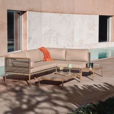 The John Lewis Sahara 5-Seater Modular Corner Garden Lounge Set on a patio of a modern Mediterranean building with a pool