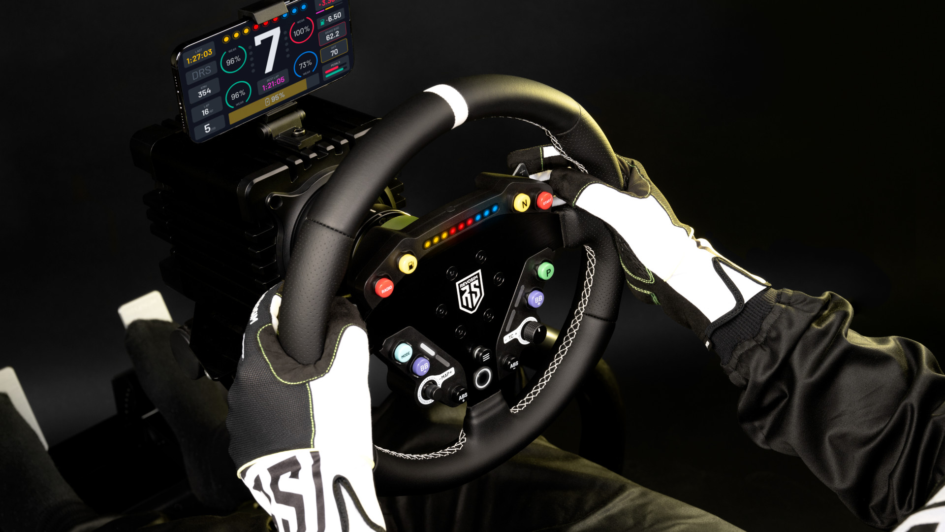 The Revosim Pure racing bundle with pedals, wheel, and wheel base set up alongside a smartphone dashboard