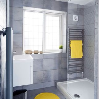 bathroom with gray tiles yellow towels and white windows