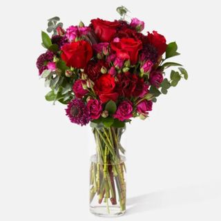 An Urban Stems Eros bouquet in a clear vase against a white background