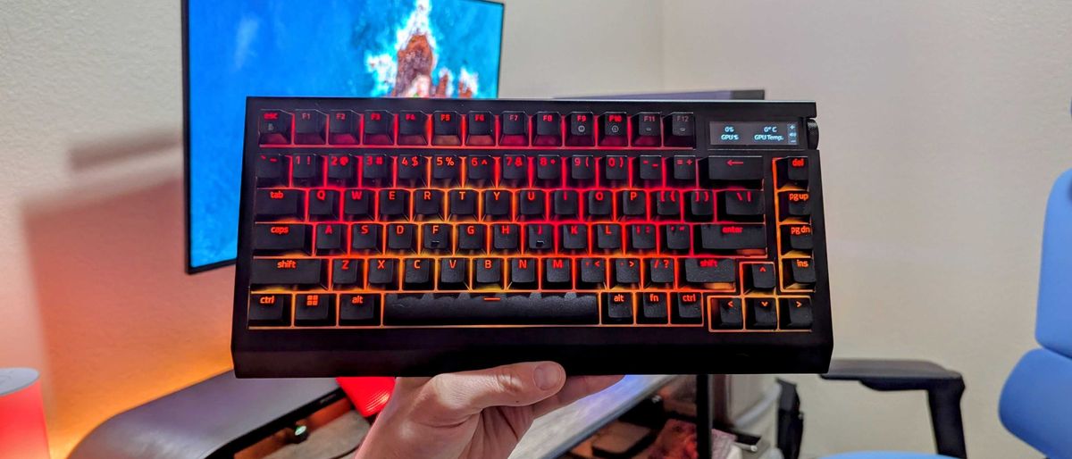 The Razer BlackWidow V4 Pro 75% held up by a hand with orange and yellow lighting.