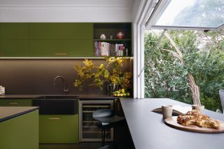A kitchen with green cabinets and a Butler sink