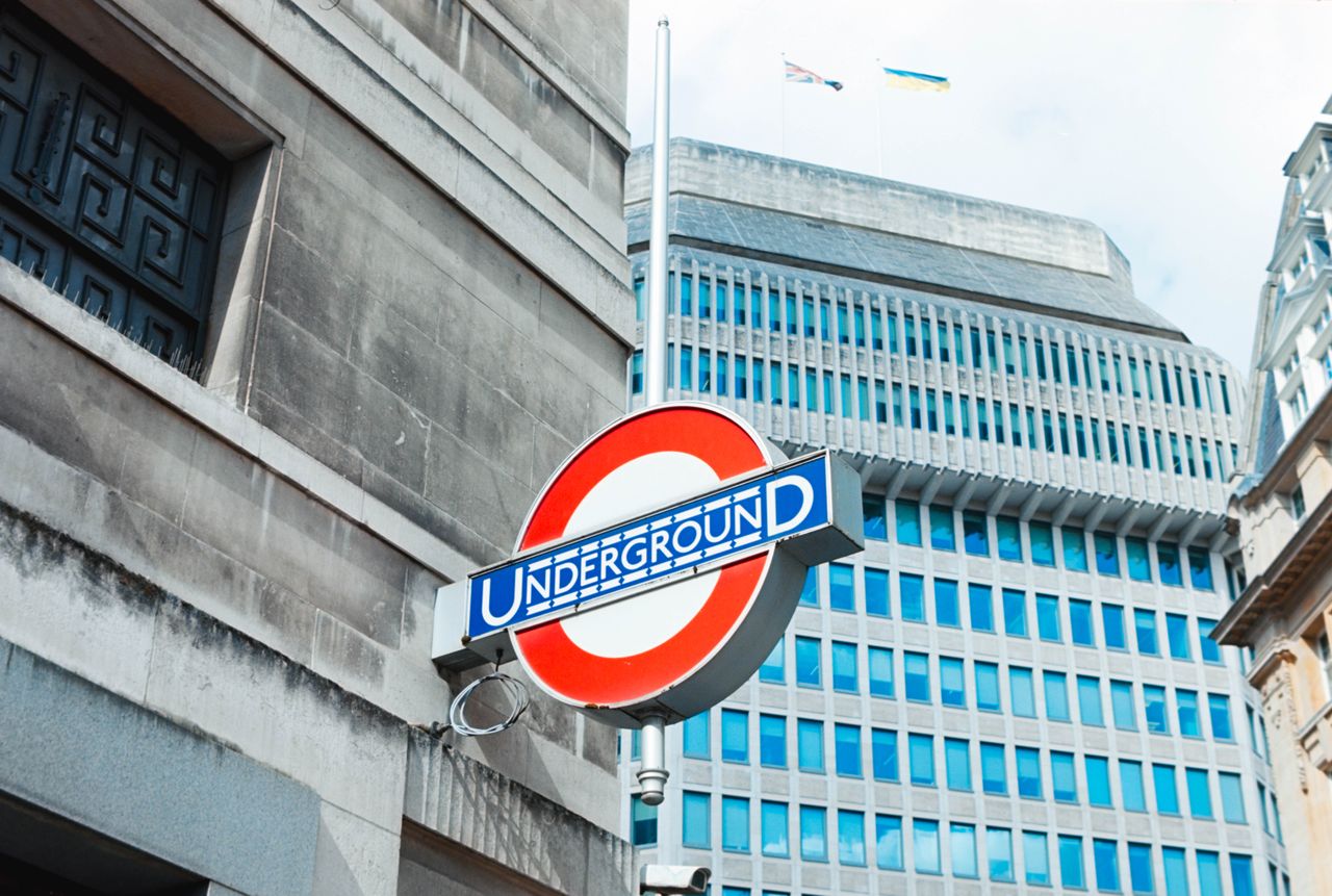 Scanned and digitized film image, using Valoi Easy 35 Pro V2 and Negative Lab Pro Lightroom plugin. Image shows a London underground sign in front of tall glass buildings