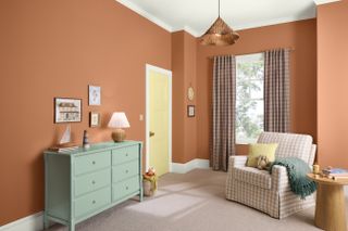 Burnt orange painted living room with blue chest of drawers