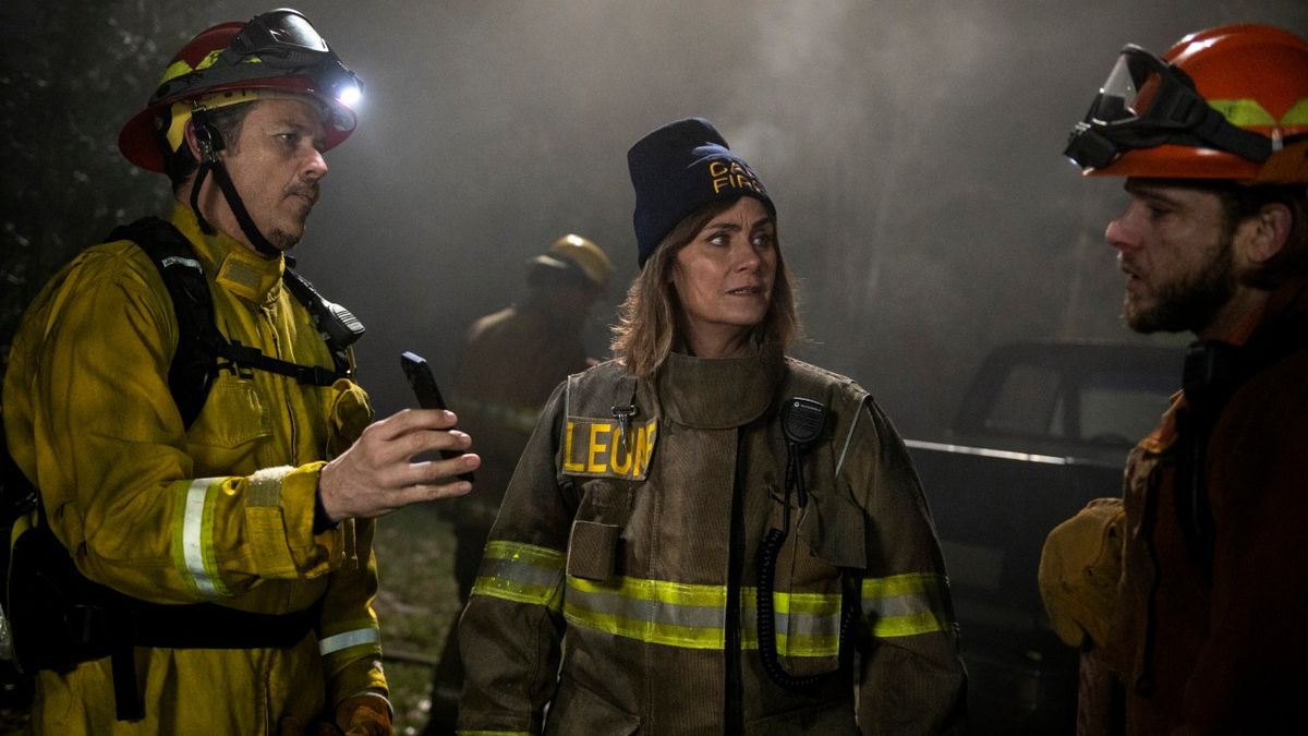 From left to right: Manny holding a phone, Sharon and Bode looking at him as they find out who the arsonist is.