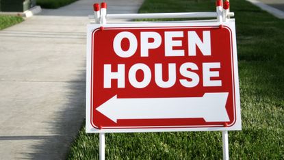 Red open house sign on grass verge