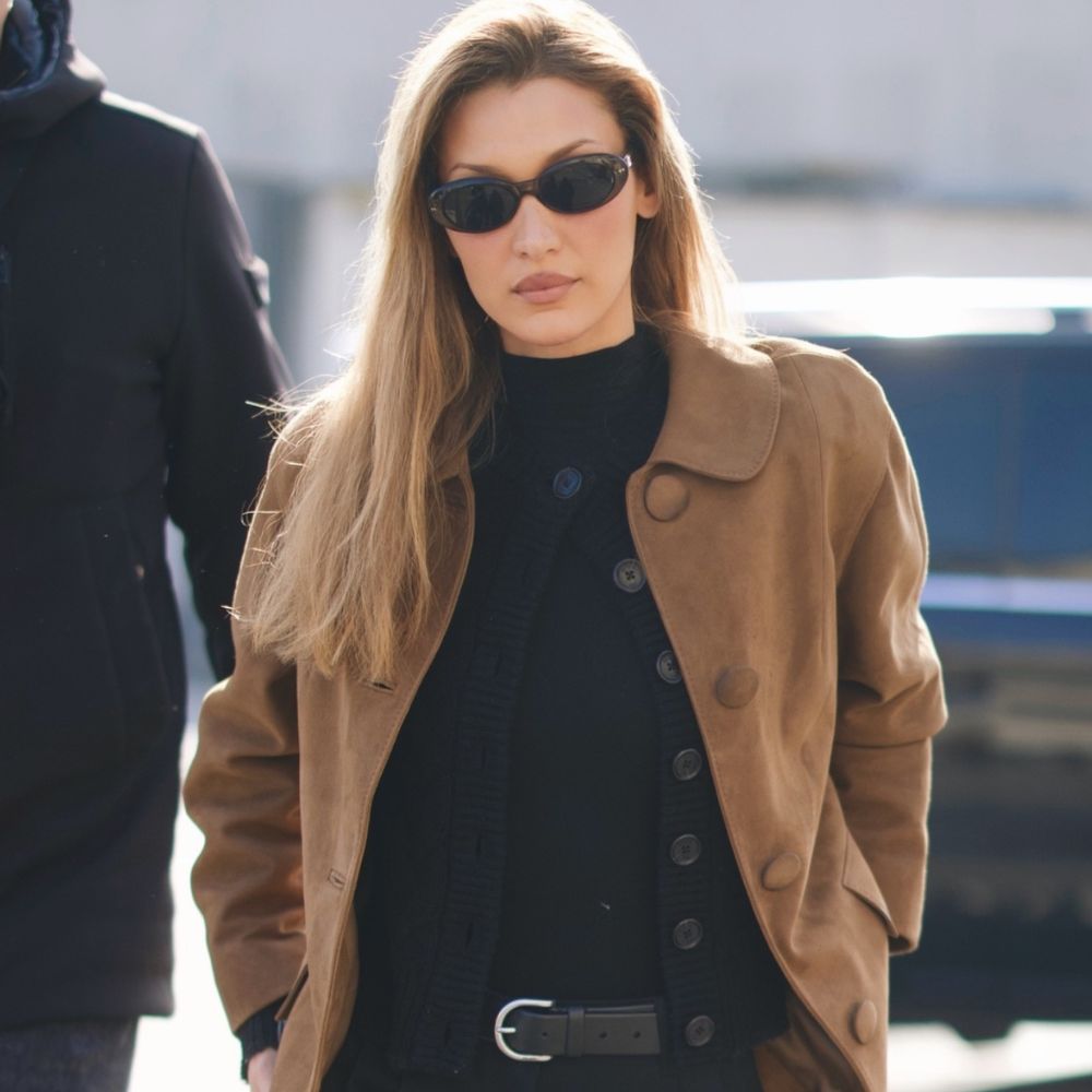 Bella Hadid wears back trousers with black almond-toe boots and suede jacket.
