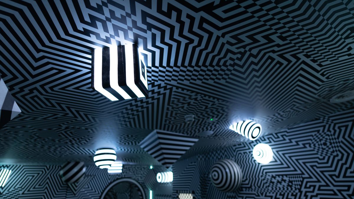 Scene from an indoor theme park, where a room features various lines and shapes to form a large optical illusion.