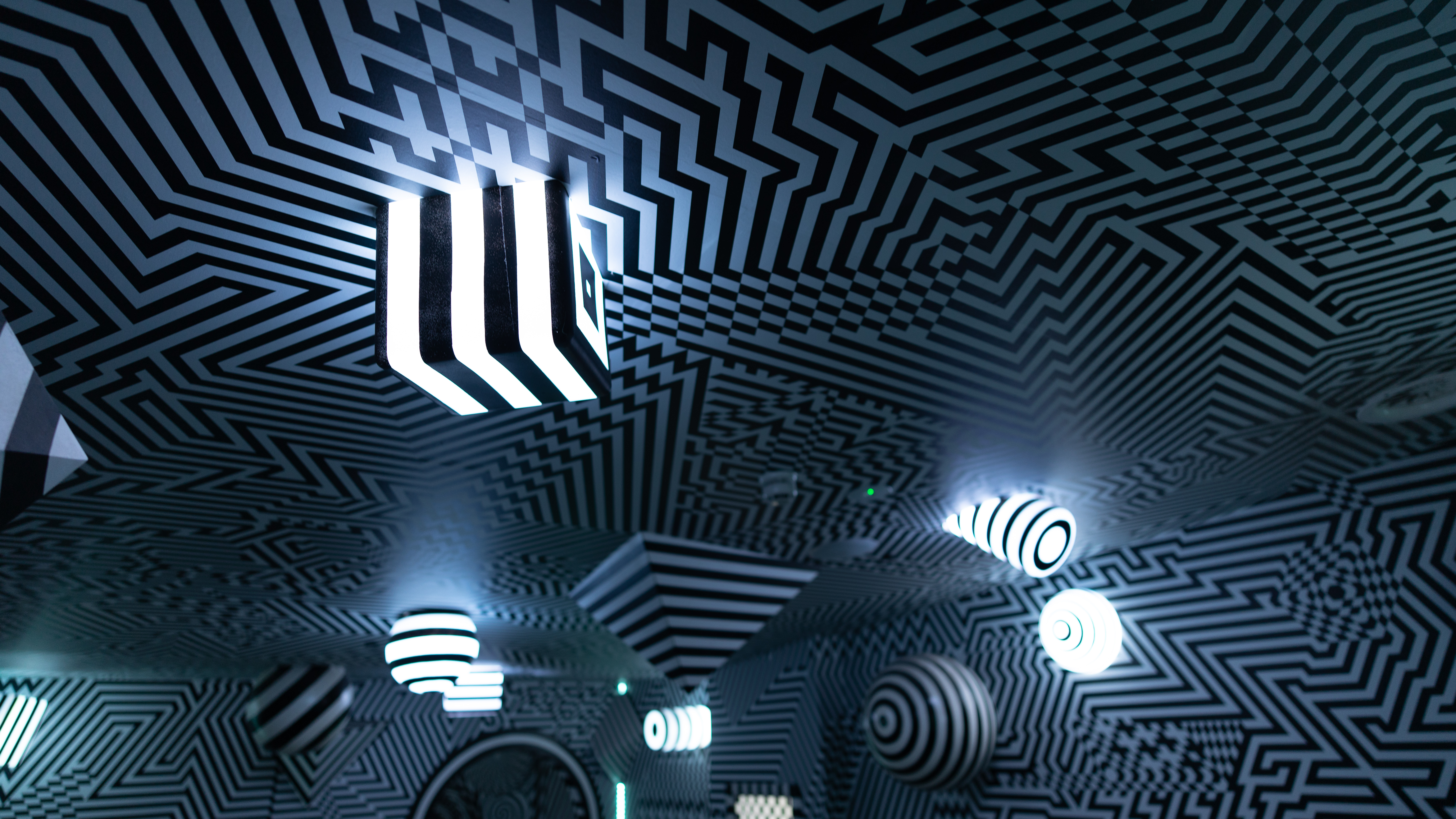 Scene from an indoor theme park, where a room features various lines and shapes to form a large optical illusion.