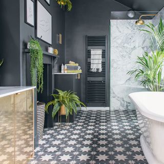 dark bathroom with patterned floor tiles and roll top bath