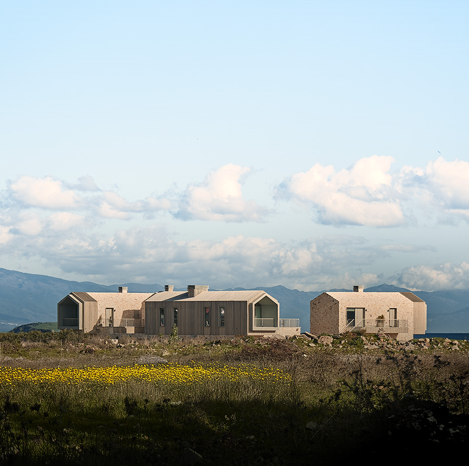 views of Pur residential recording studio, a family of structures in a cluster, made of stone and wood against blue mediterranean skies