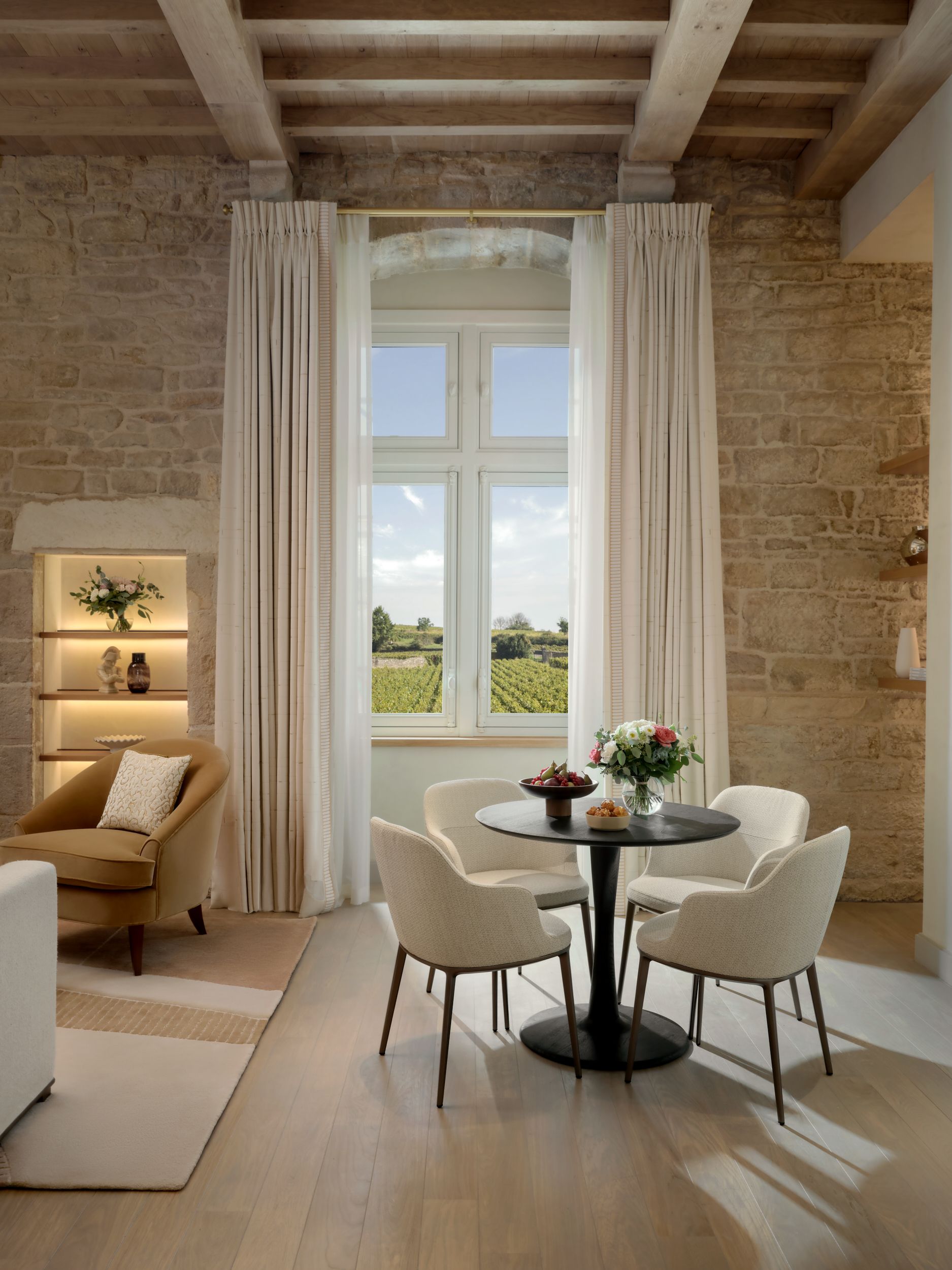 A series of images showing the history-inspired interiors of a rustic French chateau alongside outdoor, sunlit shots of buildings and the countryside.