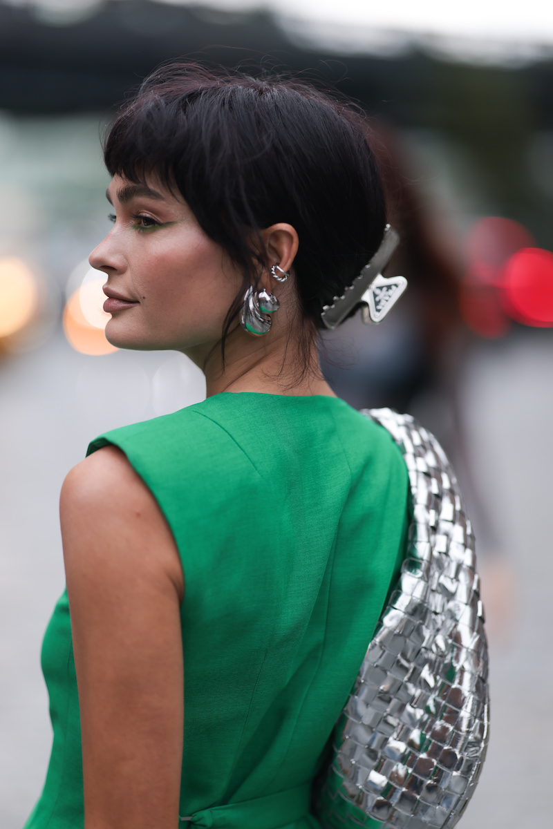 Quigley Goode seen wearing Bottega Veneta silver drop earrings and Prada silver metallic logo hair clip