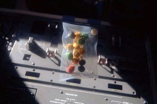 A package of candy-coated chocolate peanuts, or Peanut M&M's, floats on the flight deck of space shuttle Discovery in 1984.