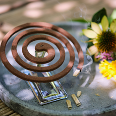 Lit mosquito coil on a garden table.