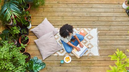 Woman sitting outside surrounded by plants looking at self care ideas