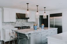 Kitchen with neutral cabinets, island with bar stools and pendant lights