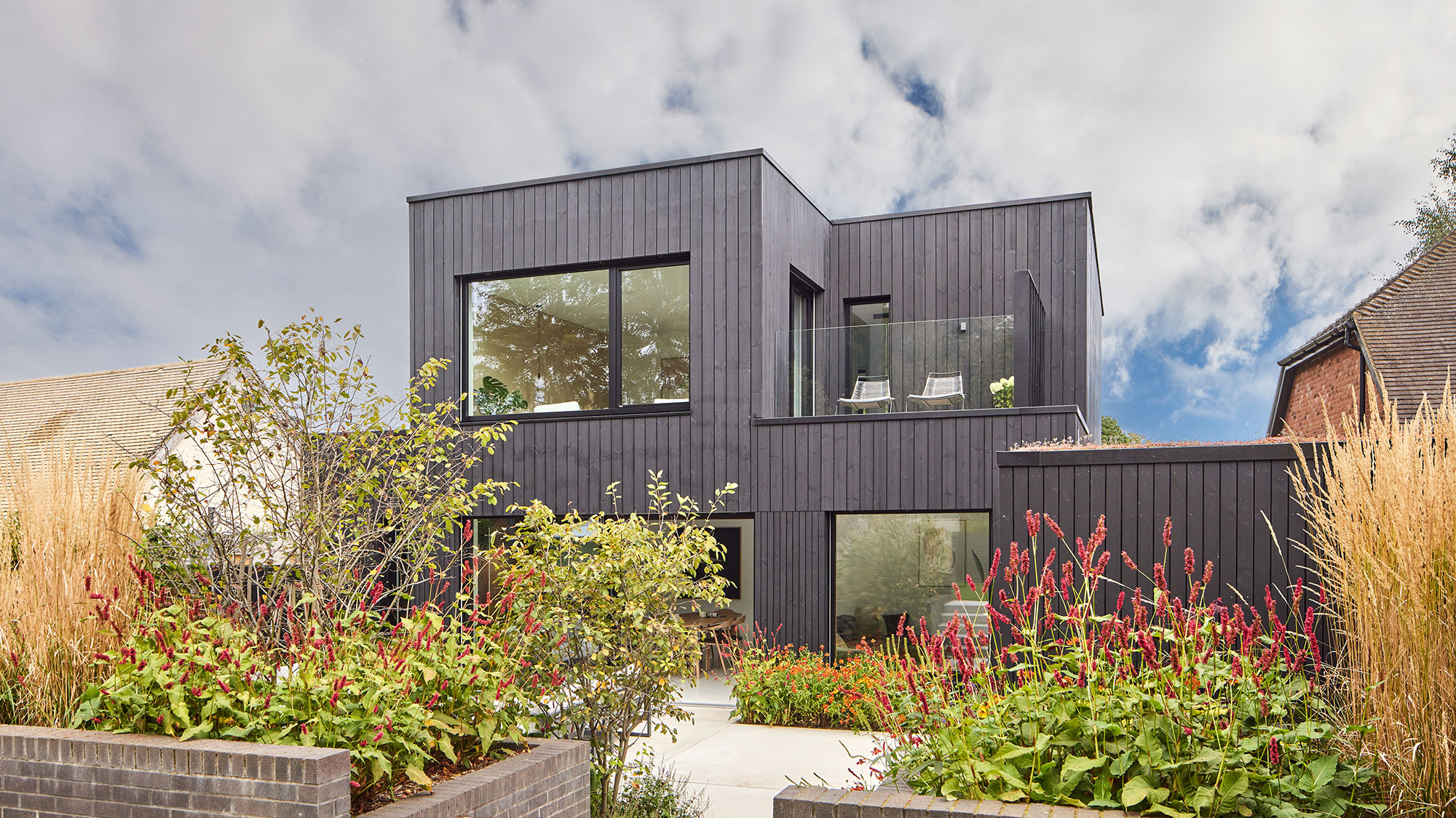modern self-build house with black timber cladding and first floor balcony