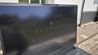 A dark grey Alienware m17 R5 gaming laptop sitting on a wooden table