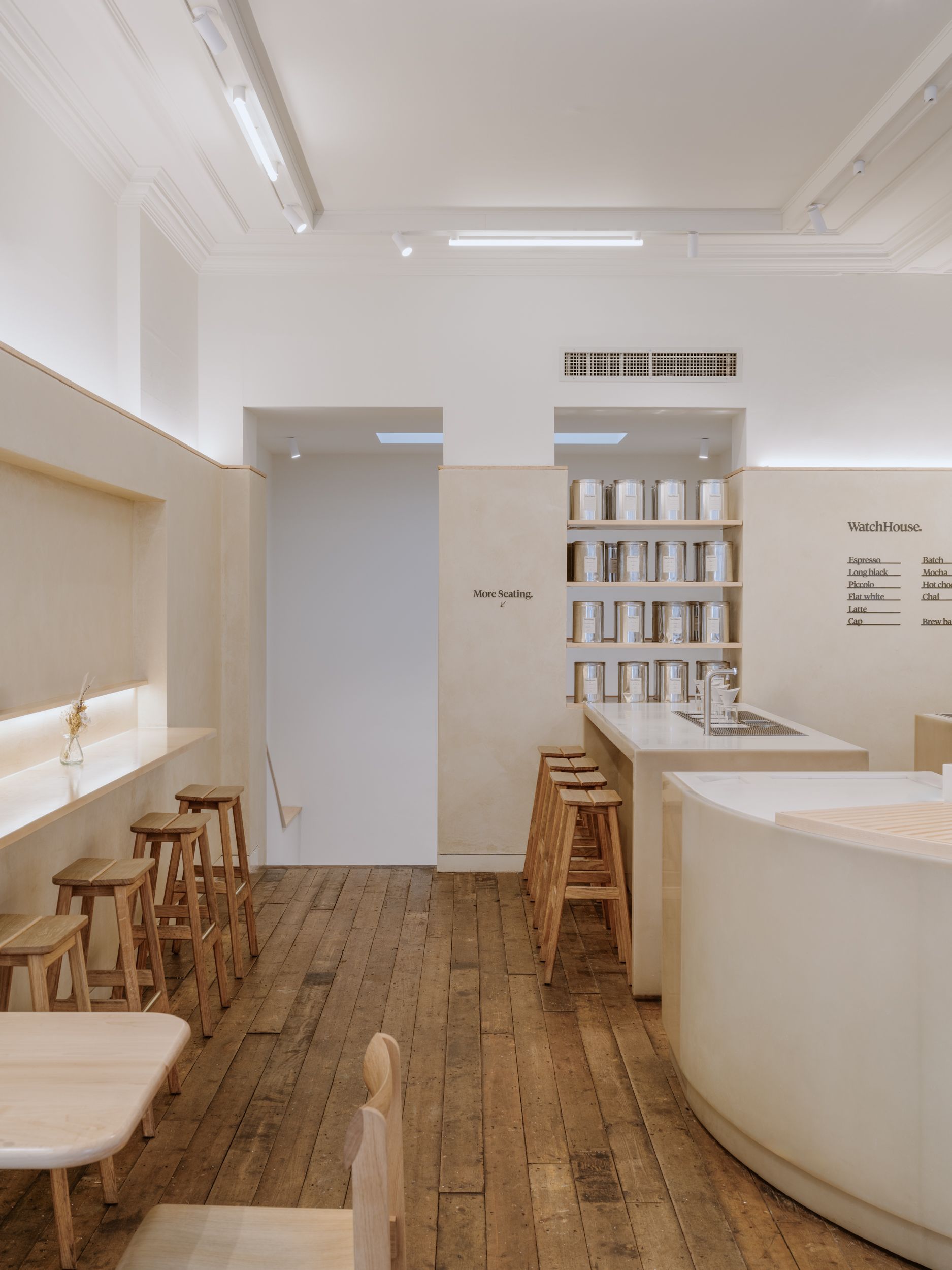 A Scandinavian-inspired cafe with wooden floors, plaster beige walls, white ceilings, and chrome accents.