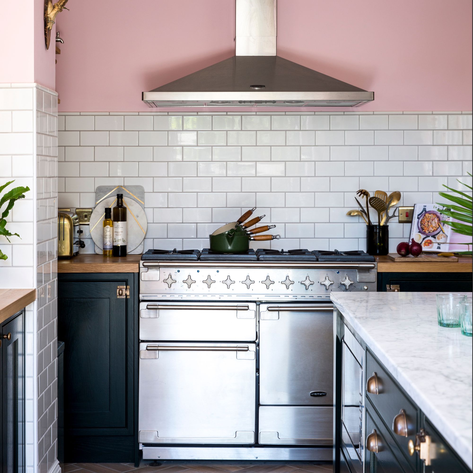 A chrome oven next to dark cabinetry in a pink kitchen