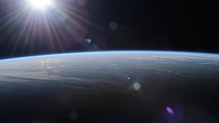 the sun creates lens flares above a blue and white earth