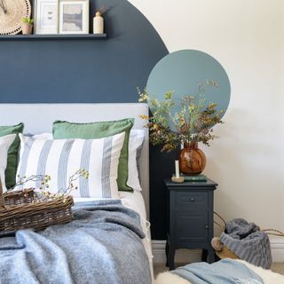 bed with blue throw in front of wall with blue painted circles