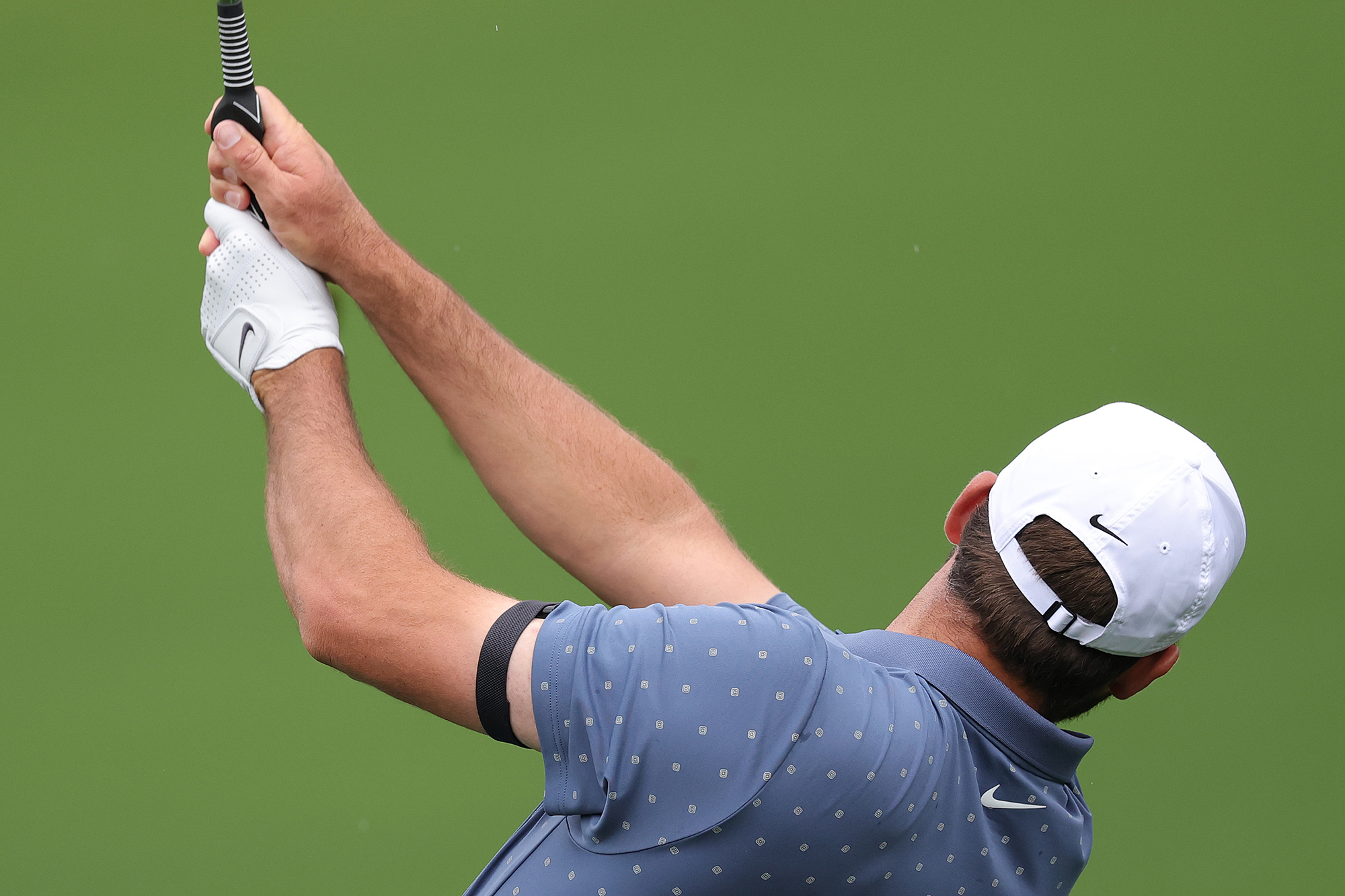 Scottie Scheffler hitting a golf shot in practice using a cheap golf training aid for improving your grip on the club