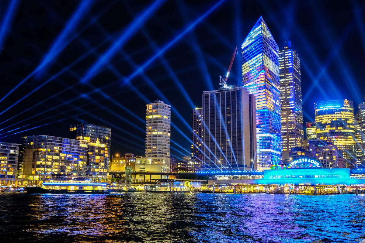 Lasers firing across a river in front of a city