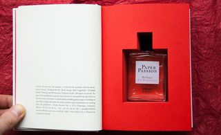Someone holding open the pages of a book to reveal a perfume bottle in a cavity cut into the pages