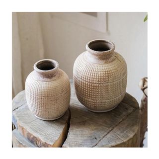 set of two cream, textured ceramic vases on wooden stool