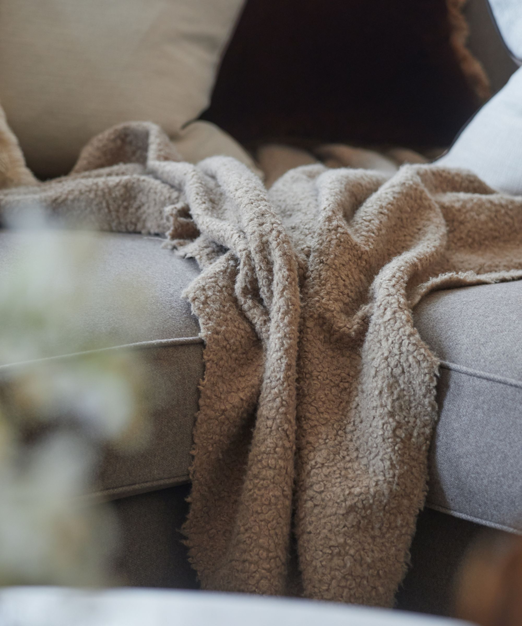 Close up of textured beige blanket on gray sofa
