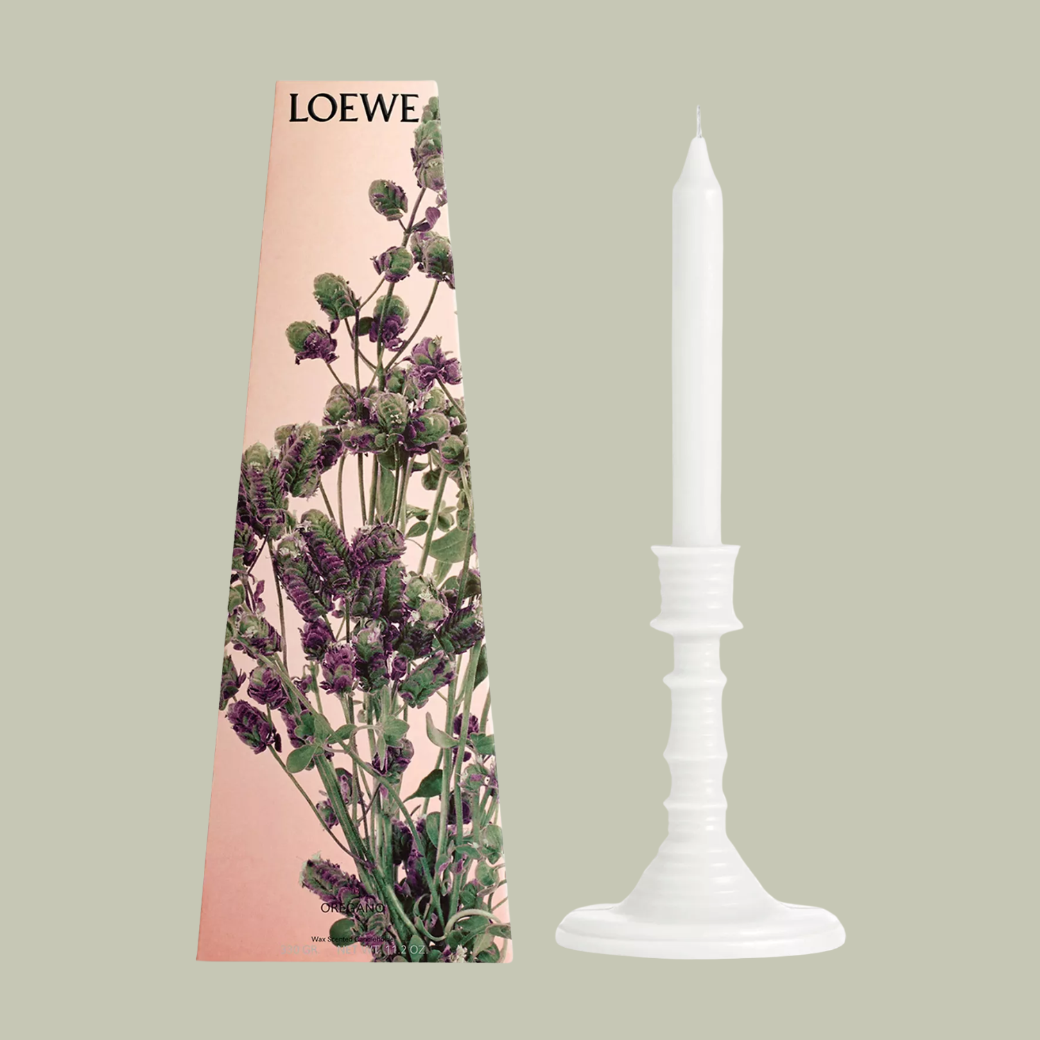 A white tapered candle beside patterned packaging