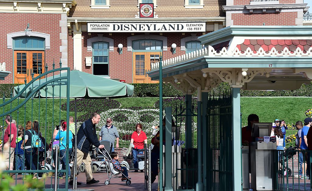 the entrance to disneyland with the park's name visible on a building behind the entrance gates