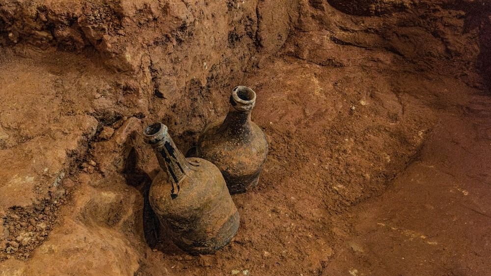 Two mud-caked glass bottles buried in dirt