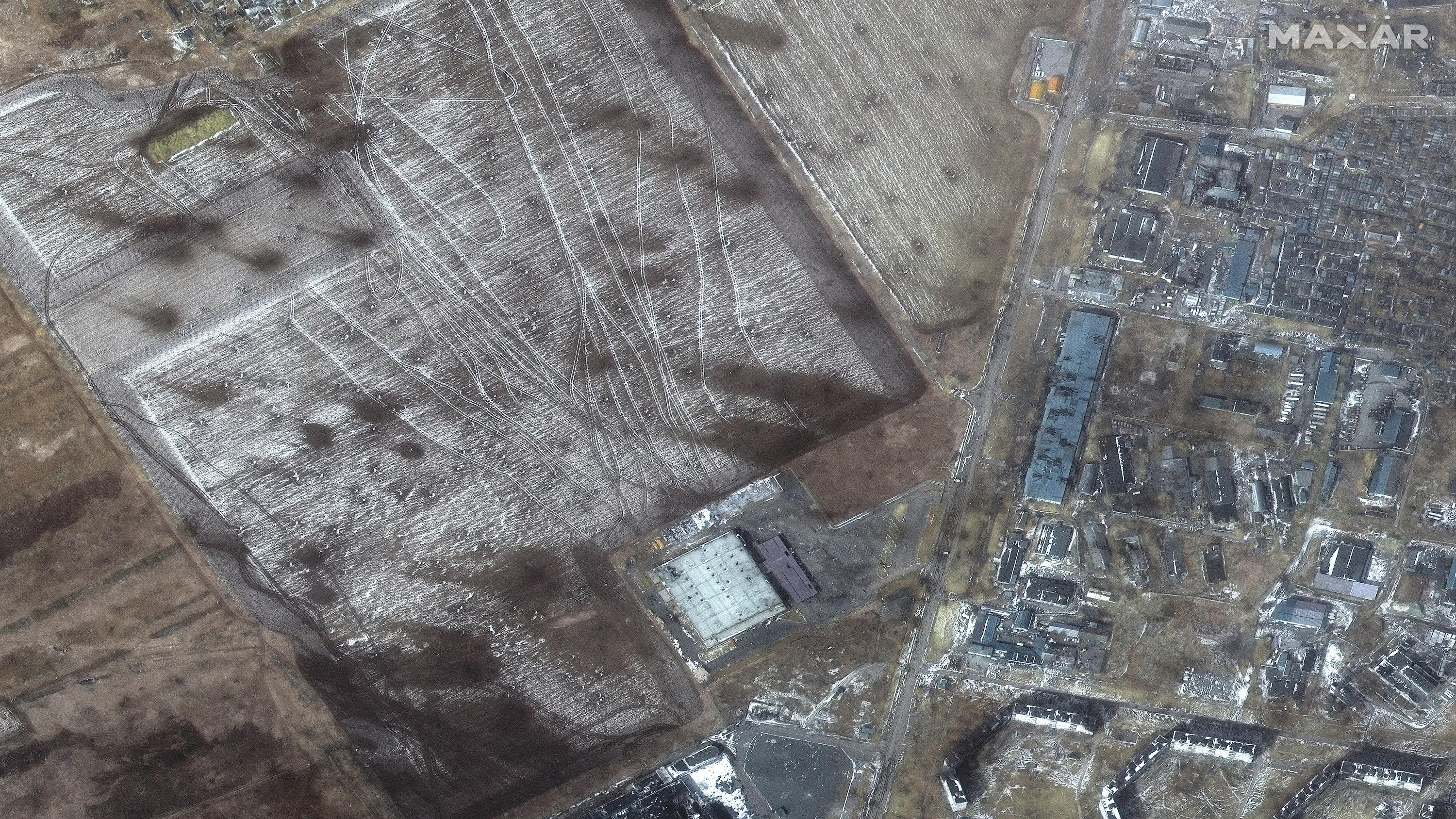 Un campo con cráteres, trazado con huellas, se muestra junto a los edificios destruidos.