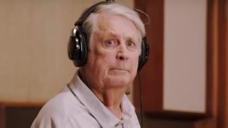 Brian Wilson sits wearing headphones while looking at the camera in Brian Wilson: Long Promised Road.