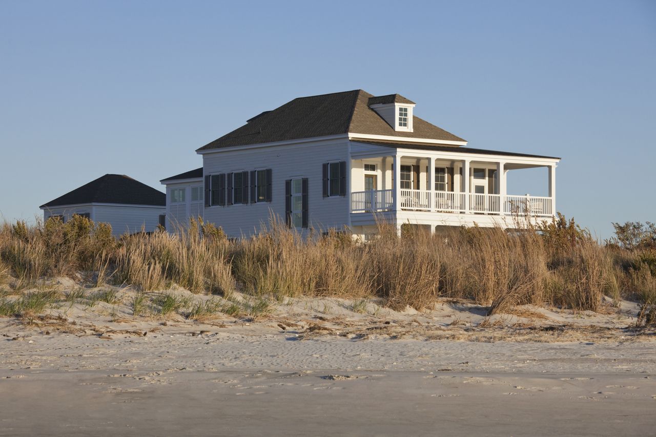 A stately home on a beachfront at dusk.