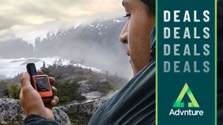 Man holding Garmin InReach Mini device inside tent in the mountains