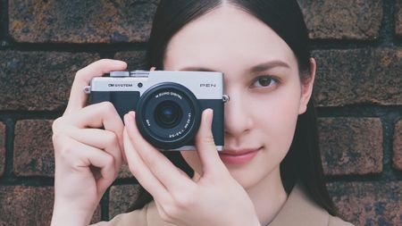 Photographer holding an OM System PEN up to eye level