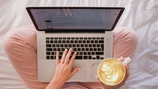 woman sitting on bed blogging