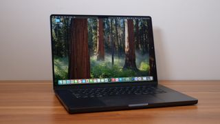 Apple MacBook Pro 16 (M4 Pro, 2024) angled toward the camera on a wooden desk and white background.