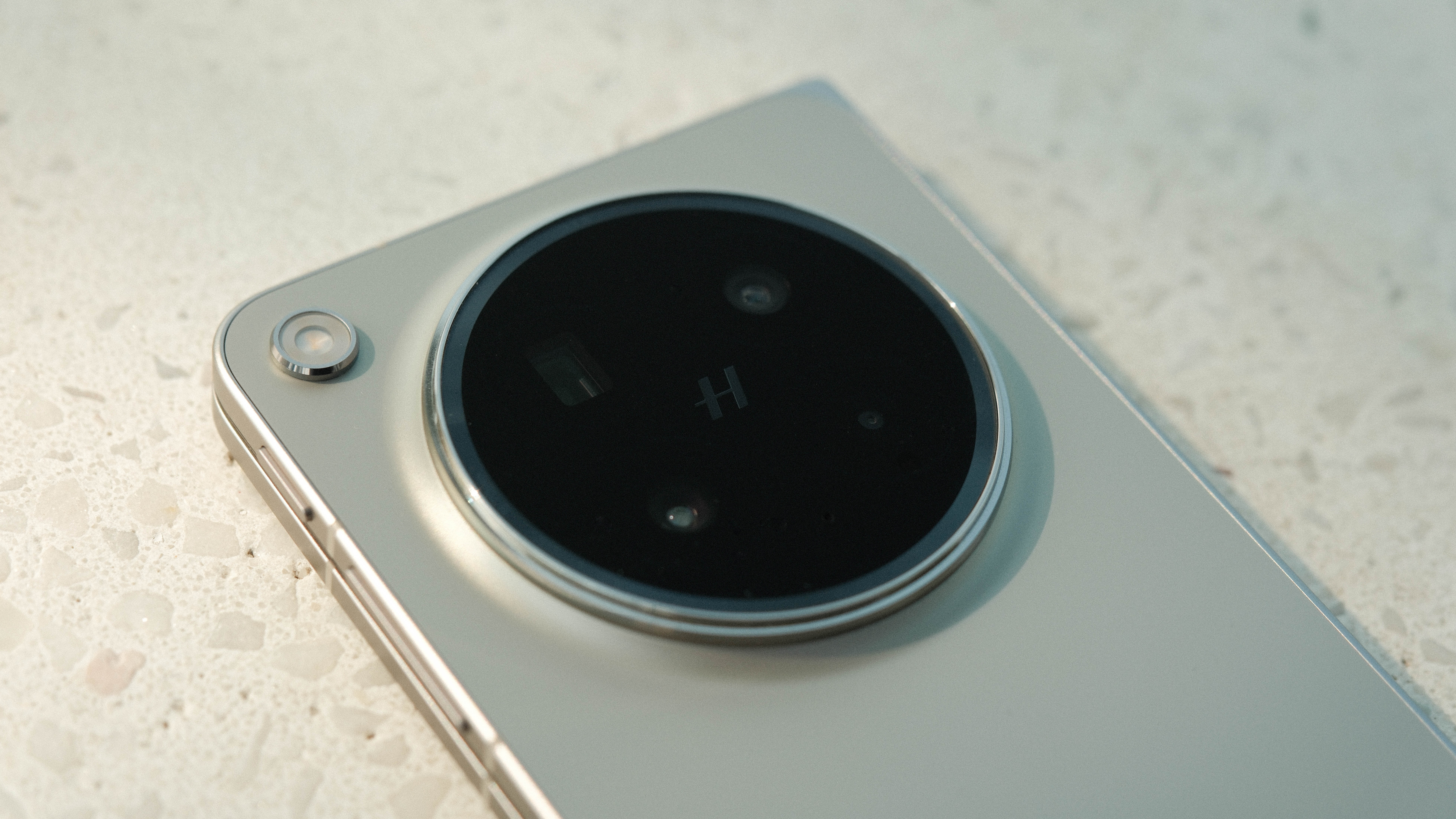 A detailed close-up of the circular camera island on the back of the device. The "H" logo is centered, surrounded by multiple camera lenses and sensors behind a dark glass cover.