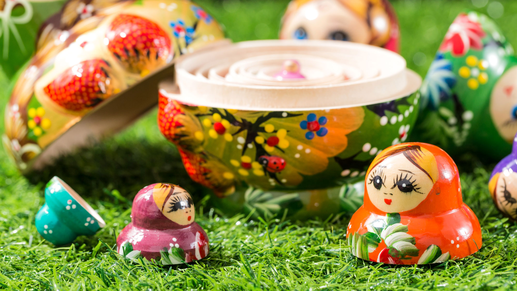 Russian dolls split apart showing central doll on grass